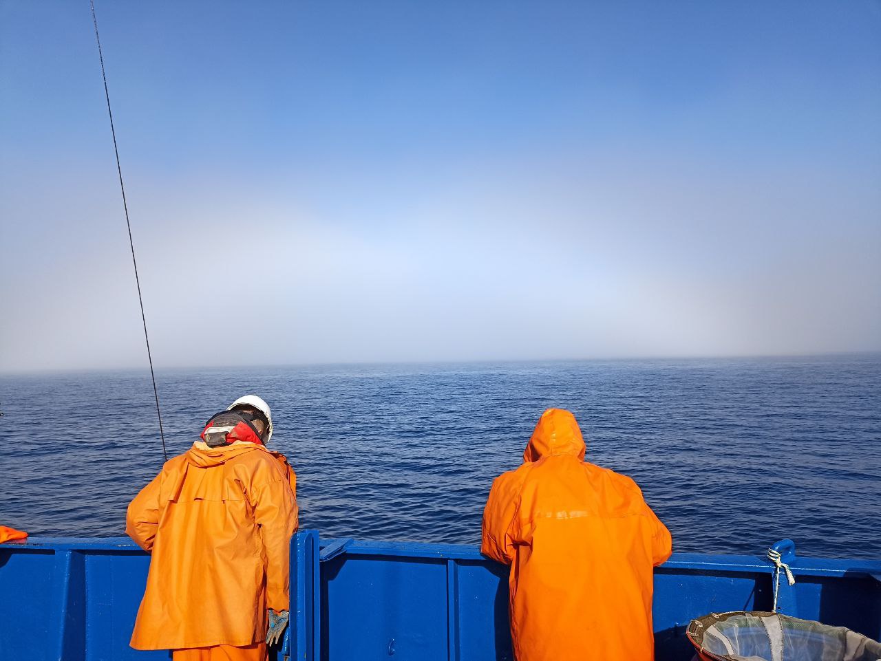 Гидробиологи ждут, пока лебёдка поднимет черпак на фоне Арктического гало
